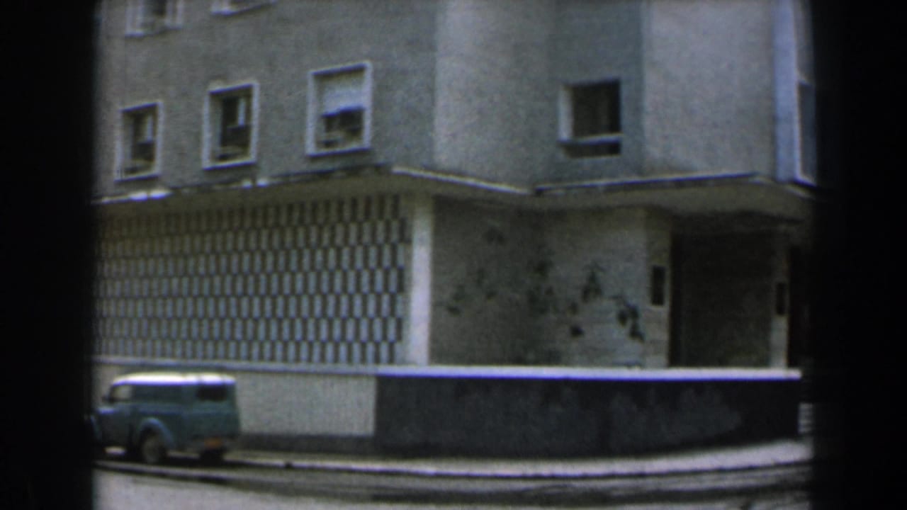 Corner of the same building with a van parked along the curb.