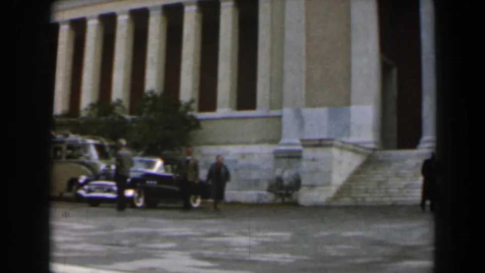 1960 Israel street-level view of people and mid-century cars gathered near the steps of a large columned civic building.