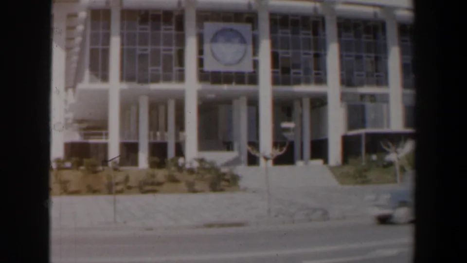1960 Israel street view of a modernist institutional-looking building with columns, gridded windows, sidewalk, and roadway.