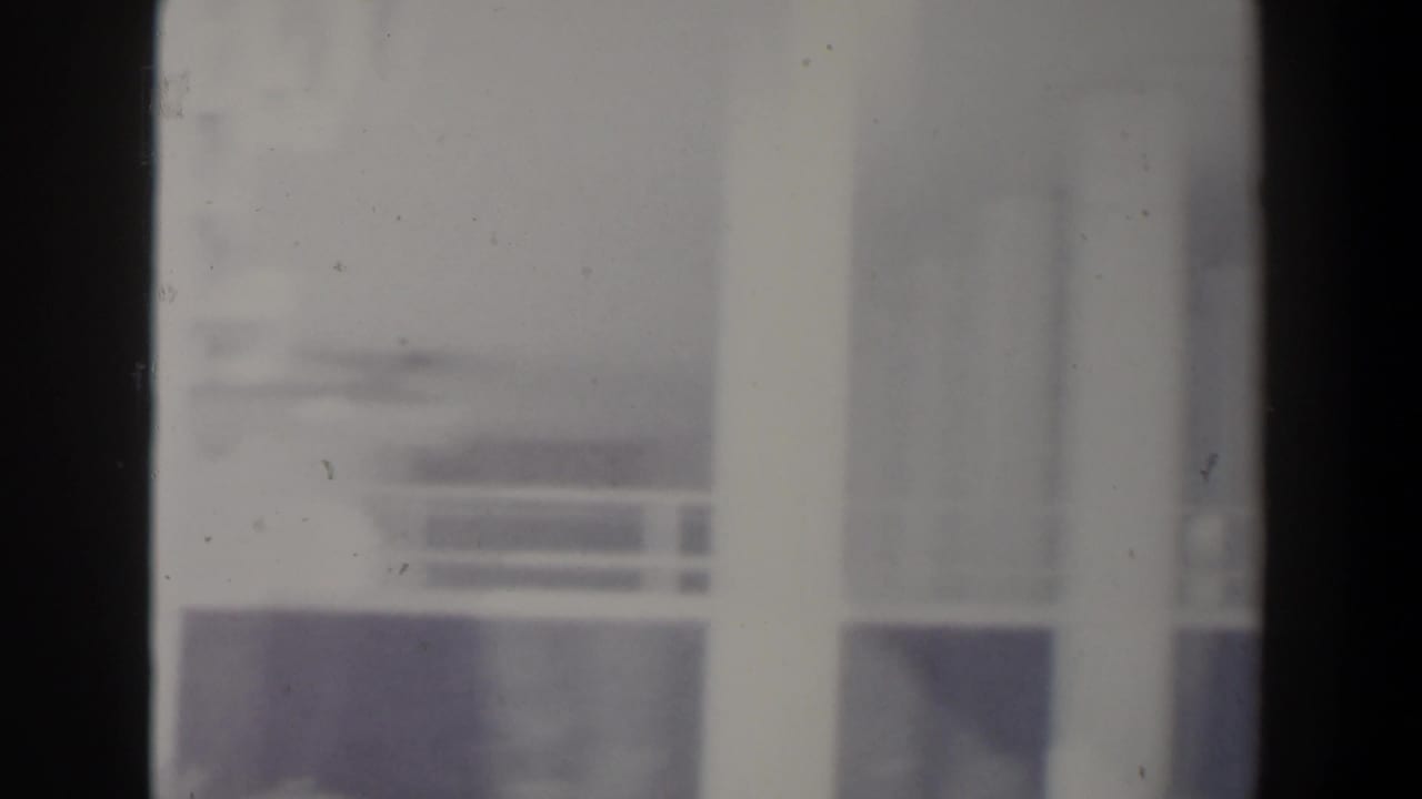 Soft, overexposed view of a white building facade and windows near the film edge.
