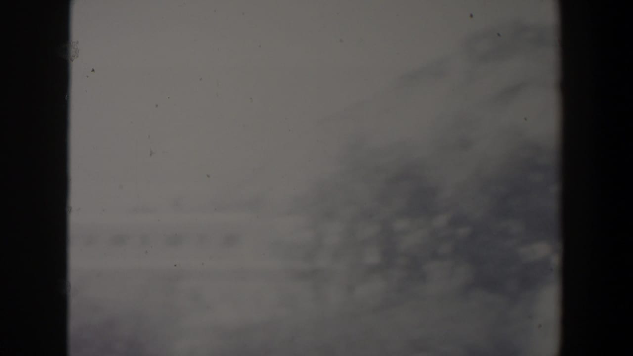 Hazy distant hills seen through dark vertical divisions with faint building shapes.