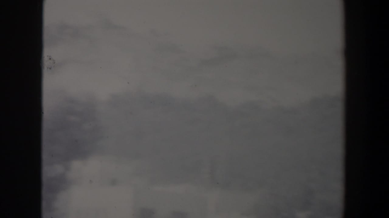 Distant ridgeline and pale building shapes partly obscured by haze and dark borders.