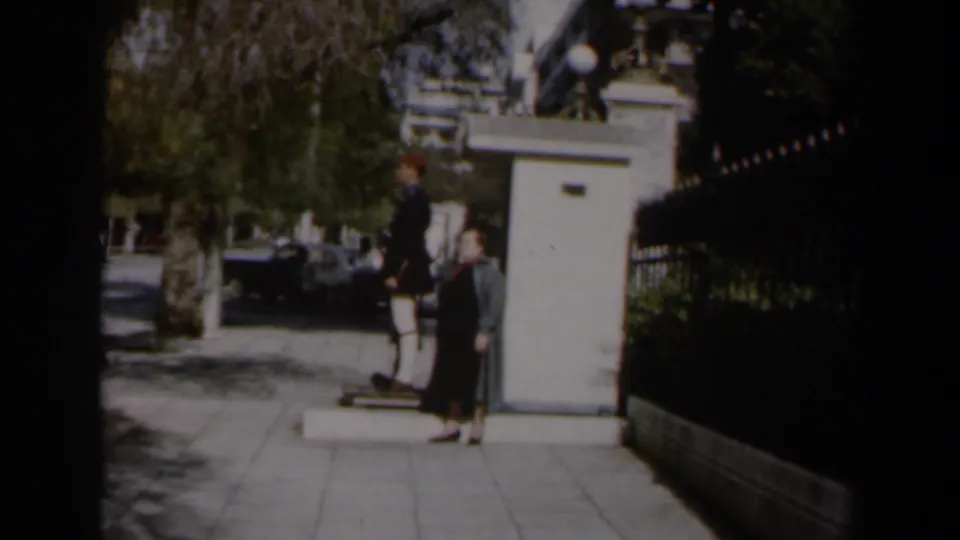 1960 Israel street scene with a uniformed sentry by a white guard box and a woman in a long coat walking nearby.