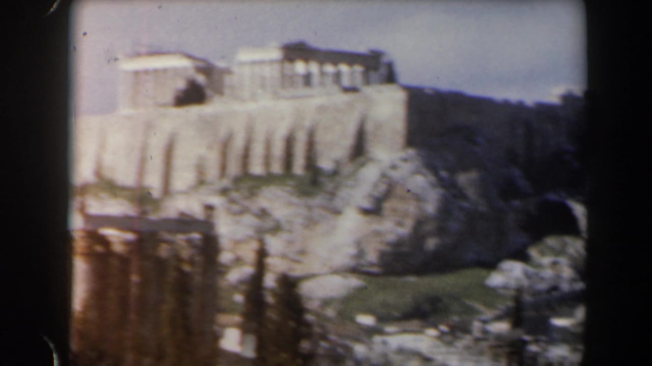 Pale hilltop structures and rocky slopes seen through a soft, faded 8mm frame.
