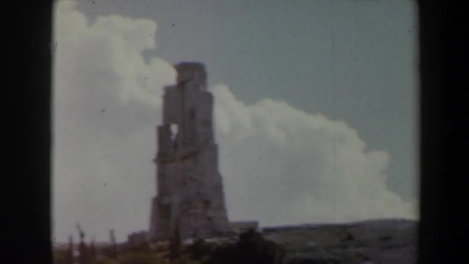 1960 8mm home-movie view in Israel showing a weathered stone ruin on elevated terrain beneath a cloudy sky.
