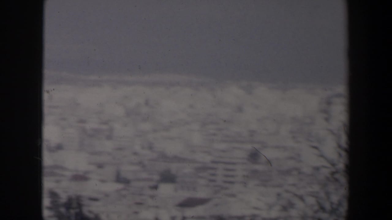 Hazy coastal city and sea viewed through dark vertical film borders.