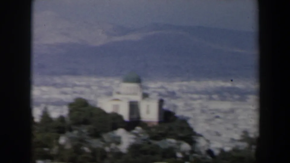 1960 Israel 8mm frame showing a green-domed foreground building set against a hazy city and hills.