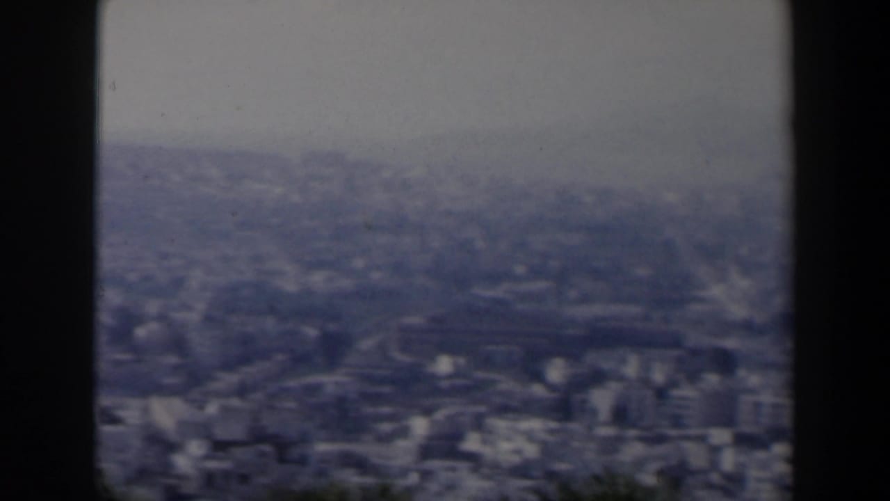 Broad hazy cityscape with dense buildings and a dark center post.
