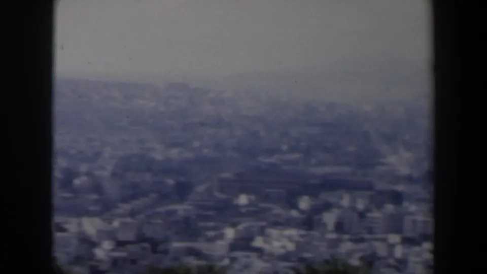 1960 Israel 8mm frame with a wide urban panorama, distant hills, and a dark vertical post dividing the view.