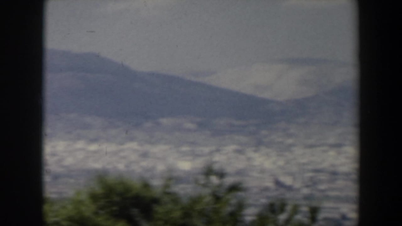 Hazy mountain backdrop and distant urban area viewed through dark vertical frame edges.