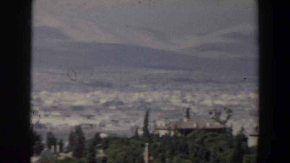 1960 Israel panoramic view showing a distant urban area, mountain ridges, trees, and a small hillside building.