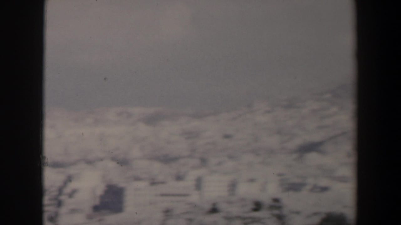 Hazy distant hillside cityscape seen through dark film borders.