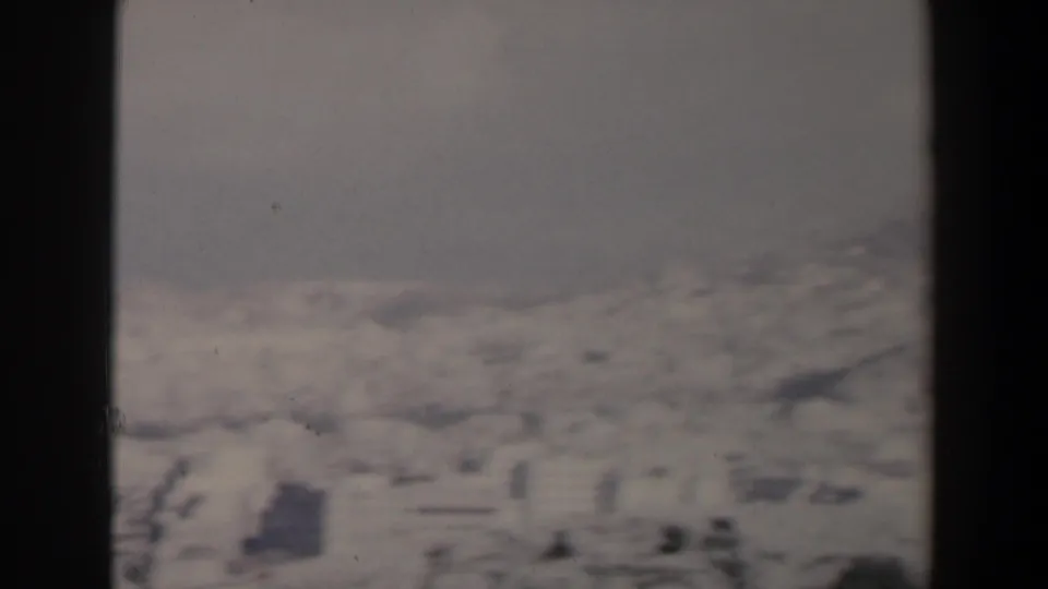 1960 Israel home-movie frame with a soft, hazy view of pale hillside buildings under an overcast sky.