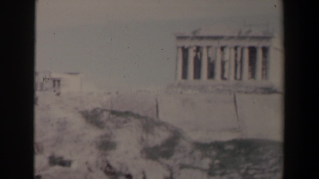 Pale classical temple with columns on a rocky hill, seen through soft 8mm framing.