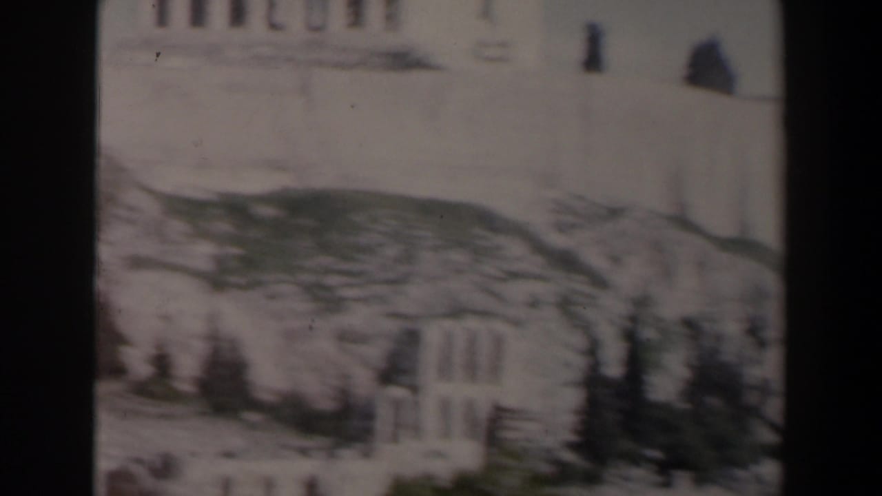 Stone ruins and a rocky hillside with dark film borders at the sides.