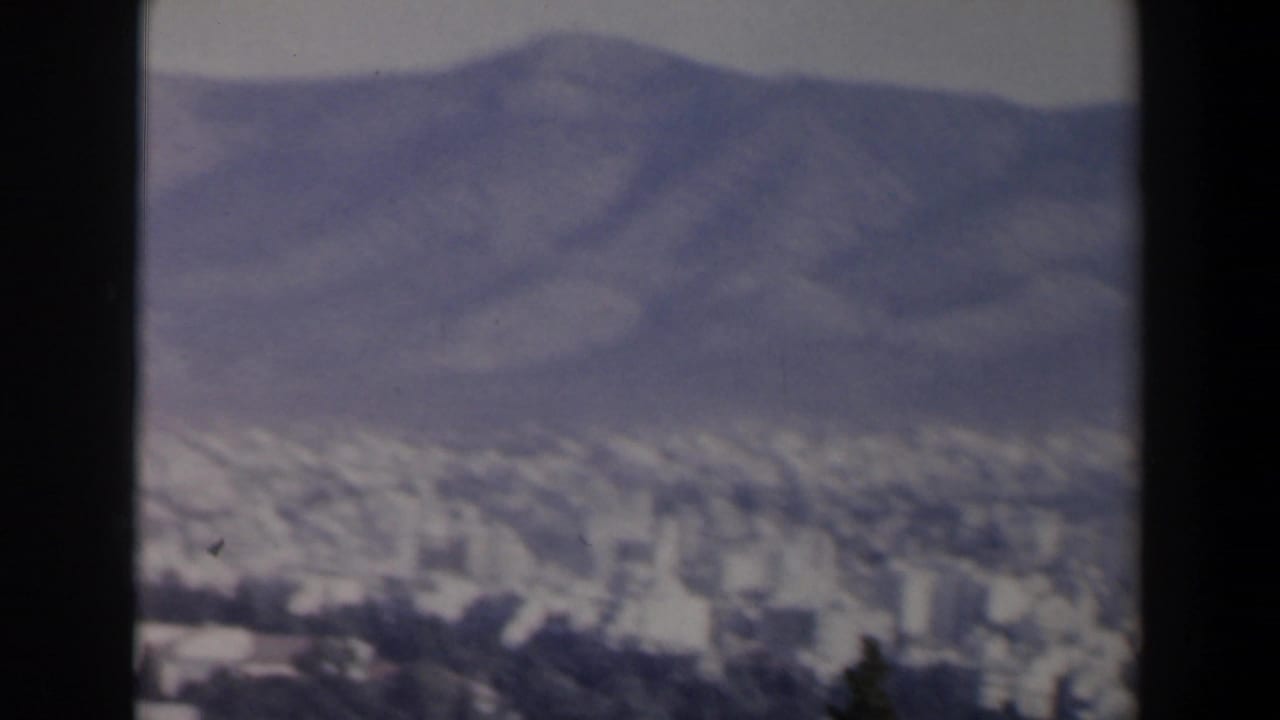 Soft distant cityscape below mountains, framed by dark 8mm contact-sheet borders.