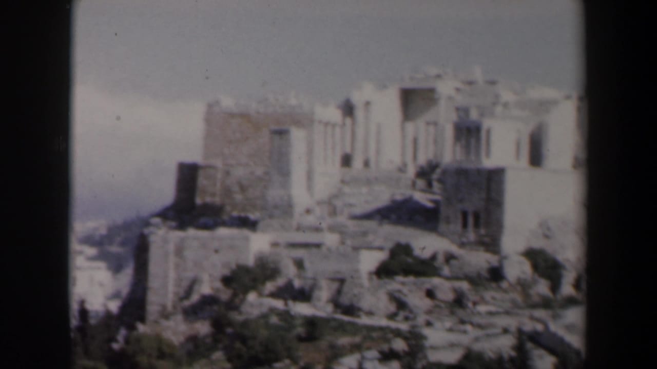 Pale stone ruin on a rocky hill with broken walls and a hazy background.