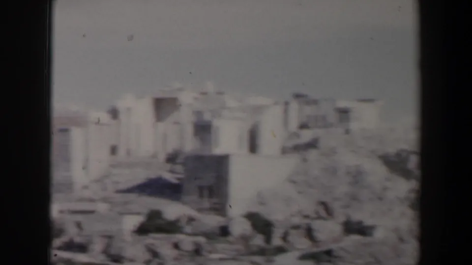 1960s 8mm view in Israel showing pale stone structures and rough rocky terrain under hazy light.