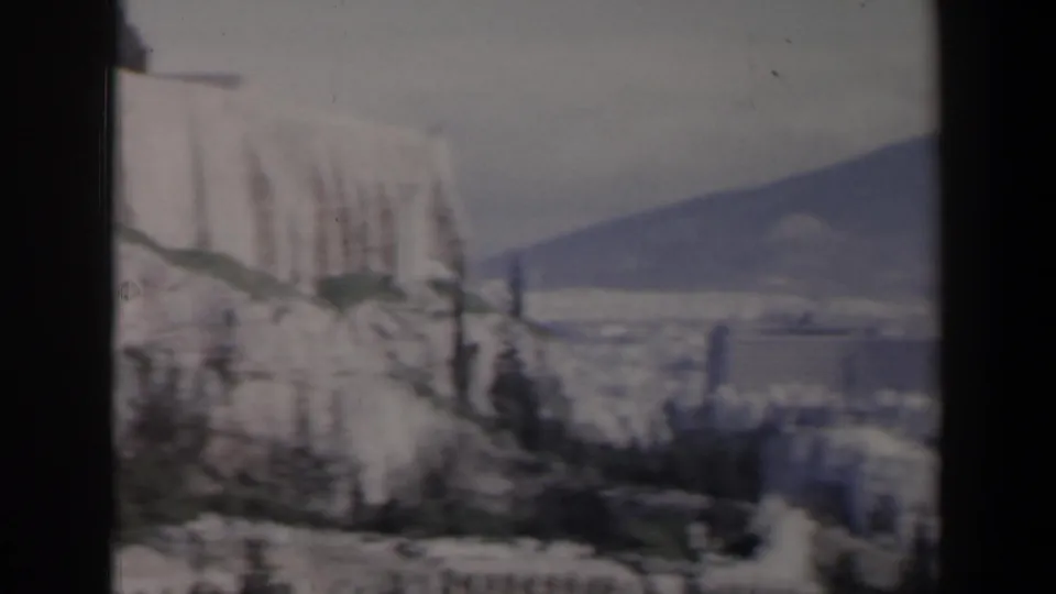 1960s Israel home-movie view of pale stone architecture on rocky ground with hazy hills in the distance.