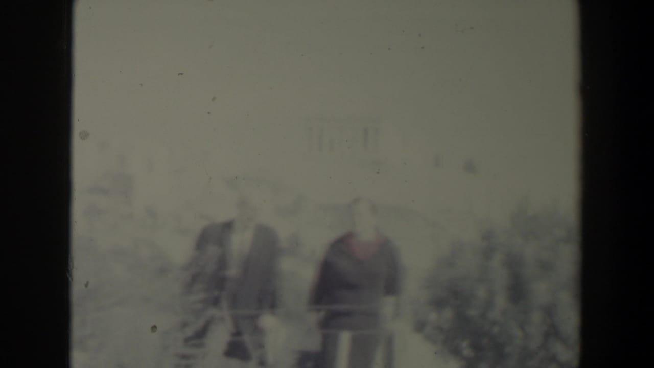 A couple stands side by side outdoors, partly softened by glare and film grain.