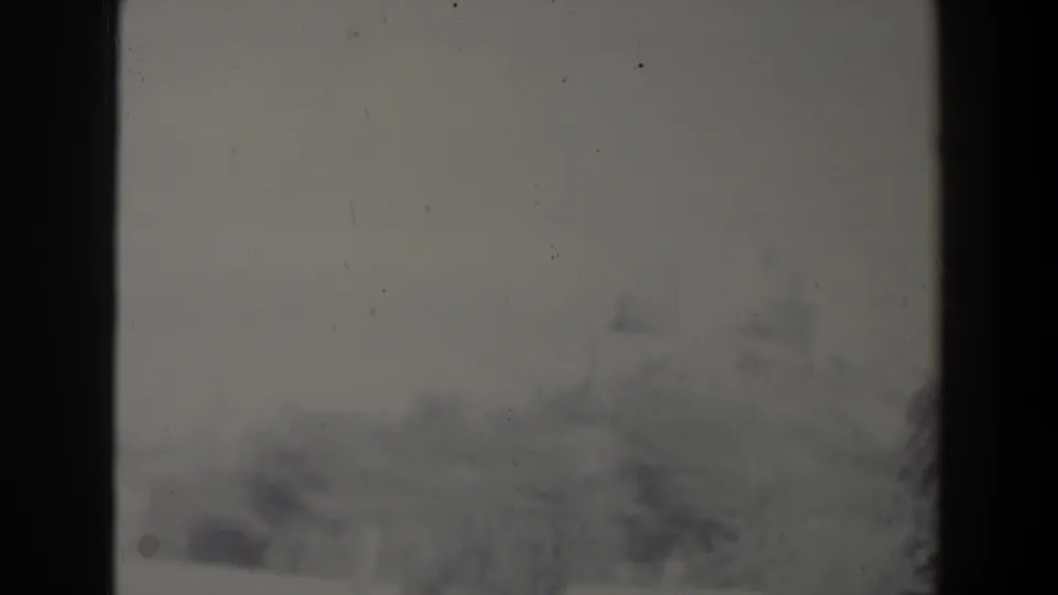 A very soft 1960 Israel home-movie frame shows a pale outdoor area with bushes and a distant low building, with no clear people centered.