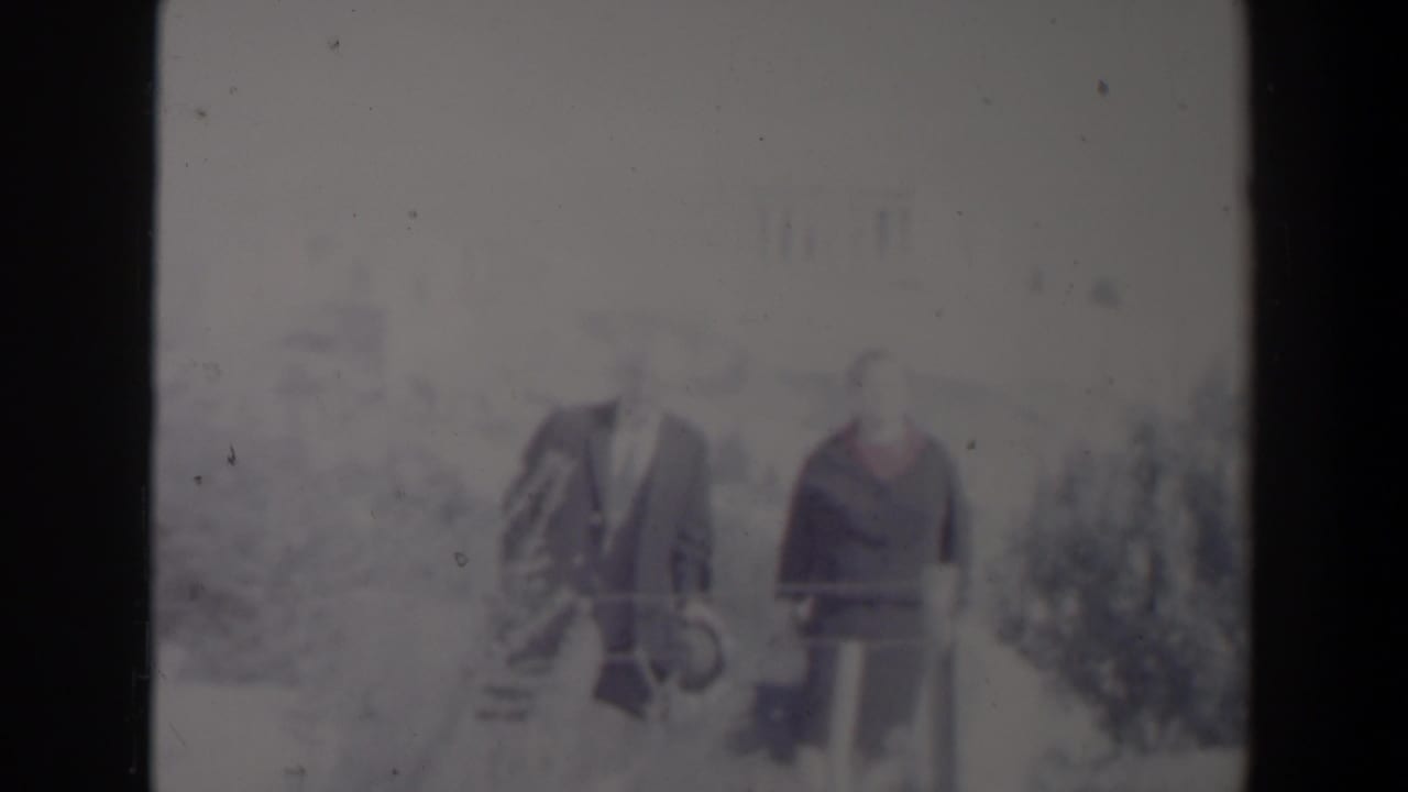 1960 Israel home-movie frame showing two adults walking outdoors in soft focus with faded color and visible film wear.