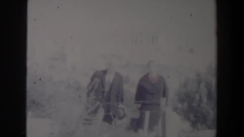 1960 Israel home-movie frame showing two adults walking outdoors in soft focus with faded color and visible film wear.