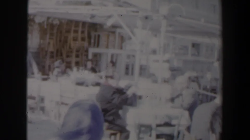 Soft 8mm frame of women working at sewing machines in a 1960 Israeli factory setting with tables and shelving visible.