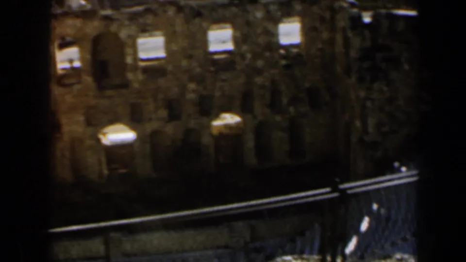 1960 Israel 8mm frame showing a weathered stone facade and iron fence from a handheld visitor viewpoint.