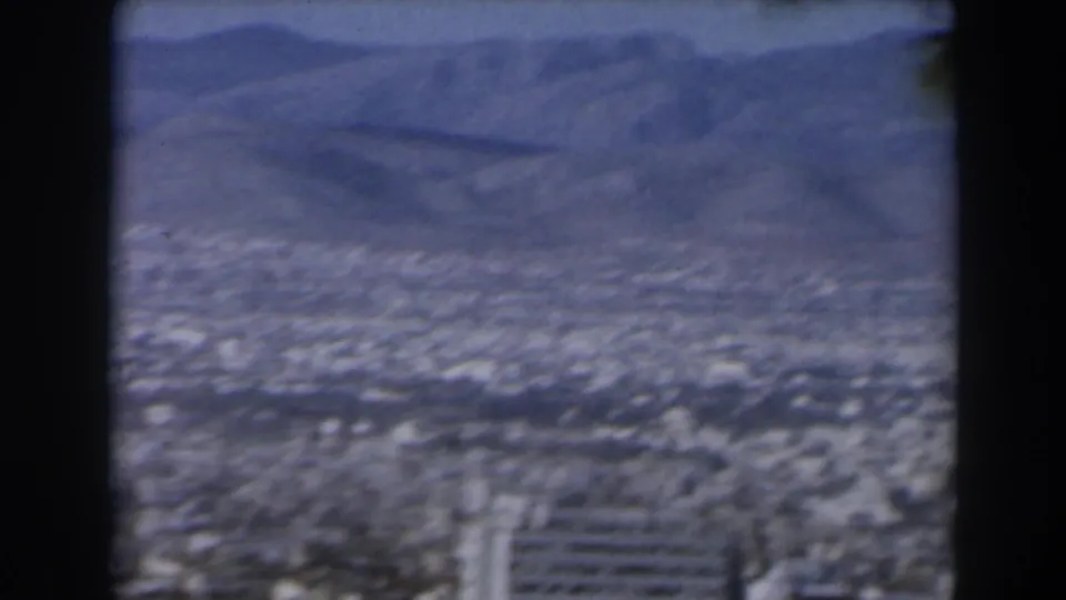 The 1960 Israel footage settles on a hazy urban landscape and mountain ridges, seen through dark vertical framing and soft 8mm color.