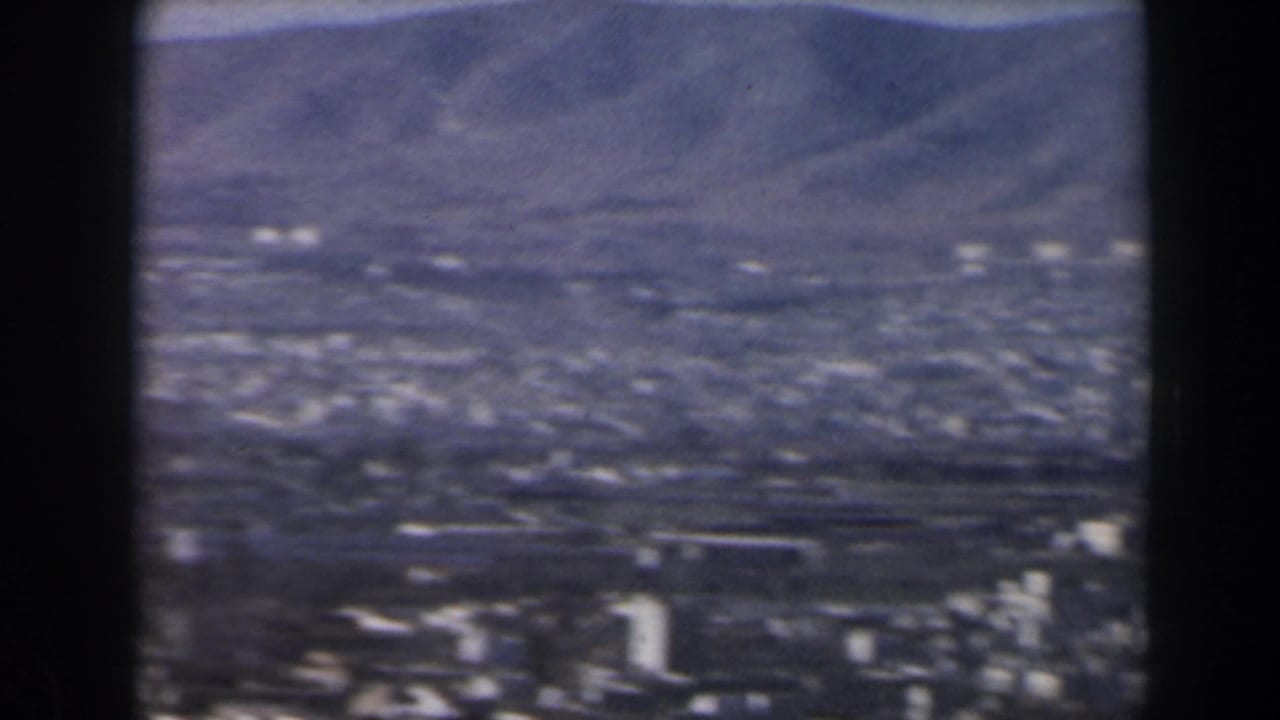 Broad city panorama with mountains behind and a few taller buildings in the foreground.