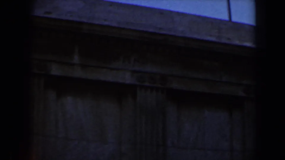 1960 Israel home-movie frame shifting from the panorama to a dark architectural wall or ledge beneath blue sky.