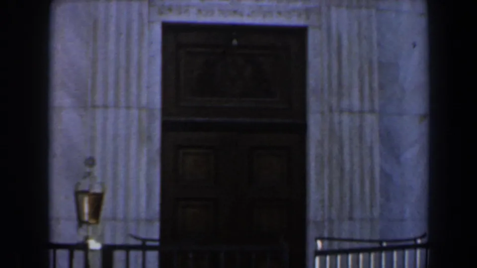 1960 Israel exterior view of a dark paneled door set into a stone entrance with fluted columns and railings.
