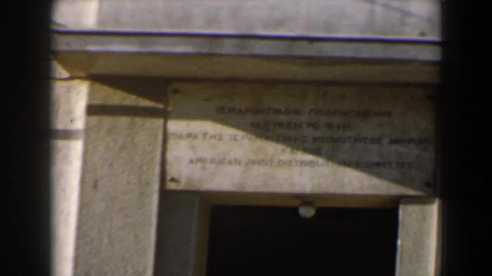 1960 Israel exterior detail of a bilingual plaque mounted over a dark entrance, with strong sun and shadow.