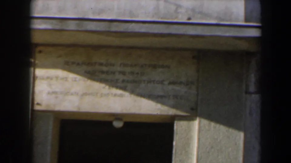 Close 8mm view of a stone plaque in Israel, with faint bilingual lettering and a dark doorway below.