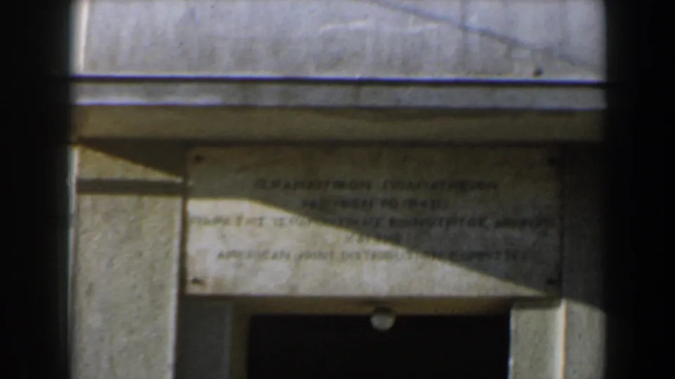 1960 Israel 8mm frame showing a weathered stone monument detail with doorway and partial foreground obstruction.