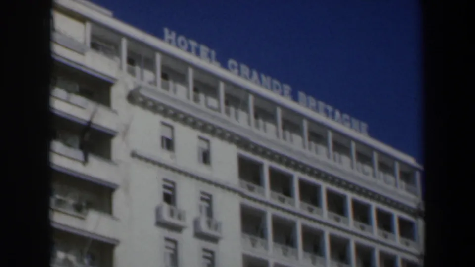 1960 Israel 8mm frame with the hotel roofline and partially readable Hotel Grande Bretagne lettering above balcony rows.
