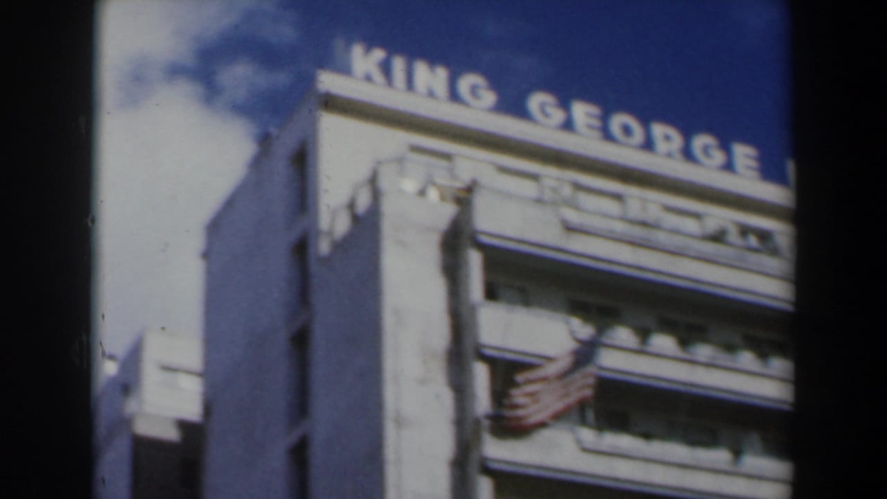 Rooftop King George Hotel sign above a white building under blue sky.