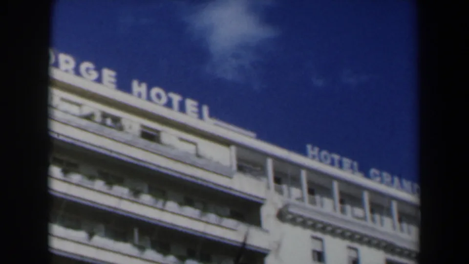 1960 Israel frame showing the King George Hotel rooftop lettering continuing across a white facade, with sky, balconies, and film-frame edges visible.