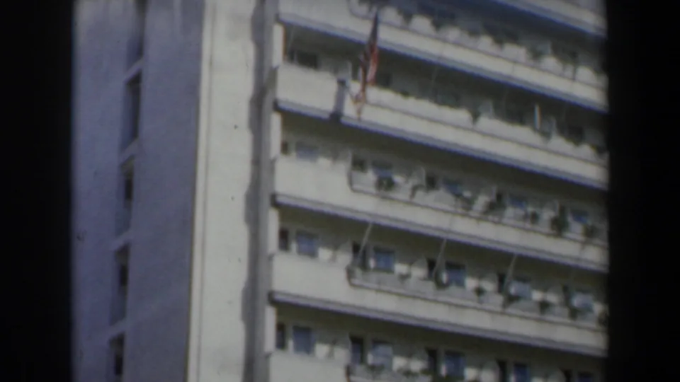 1960 Israel 8mm frame showing the Hotel Grande Bretagne facade with balconies, awnings, and a flag below the roofline.