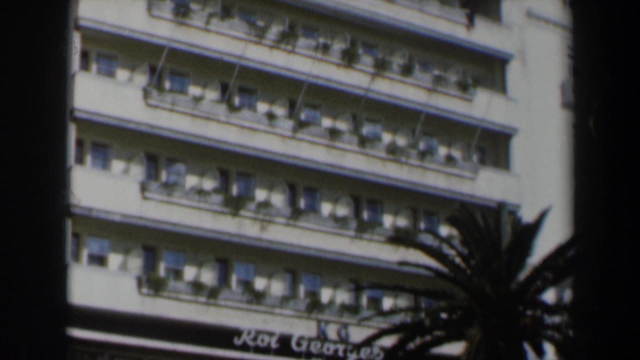 Upper stories of a hotel facade with rows of balconies and planters.