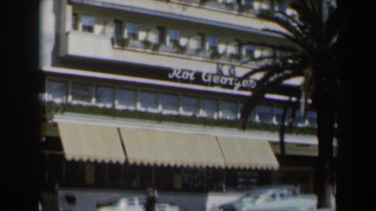 Hotel facade with Roi Georges marquee, awning, palm tree, and upper windows.