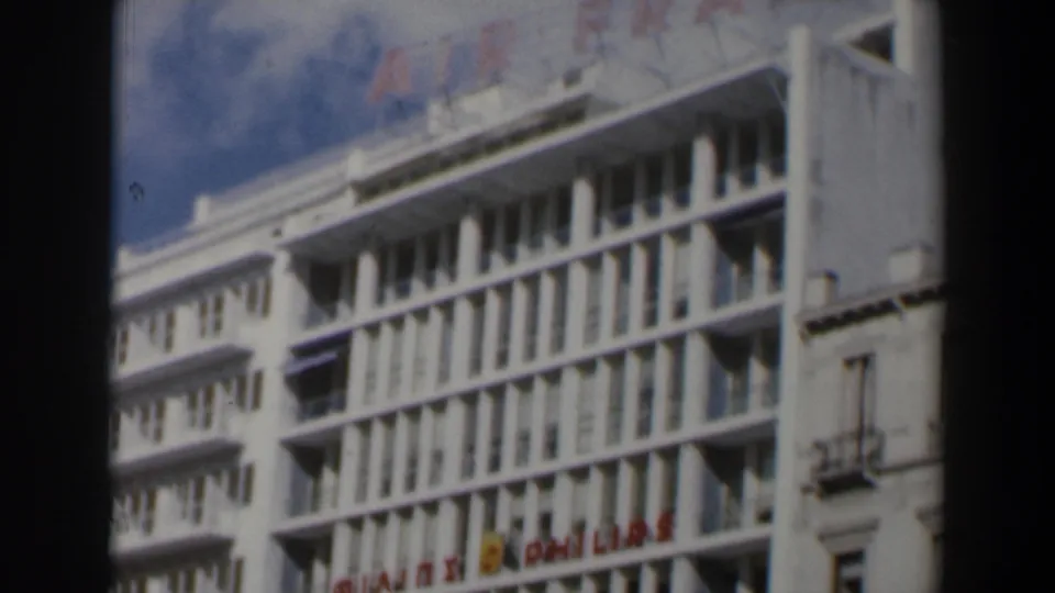 1960s Israel frame showing a white urban building facade with red Air France and Philips signs below rows of windows.
