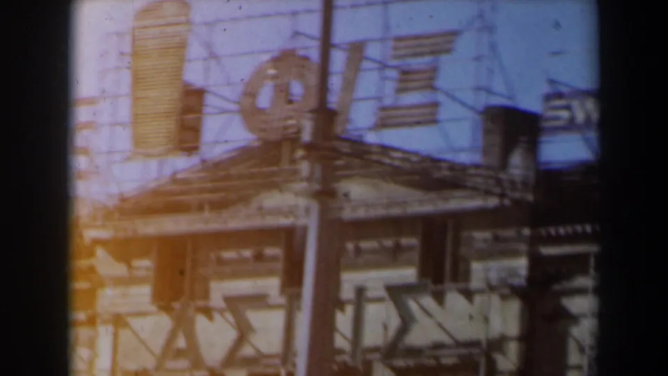 1960s Israel street storefront with awning, commercial signage, and a visible France-Soir sign on faded 8mm film.