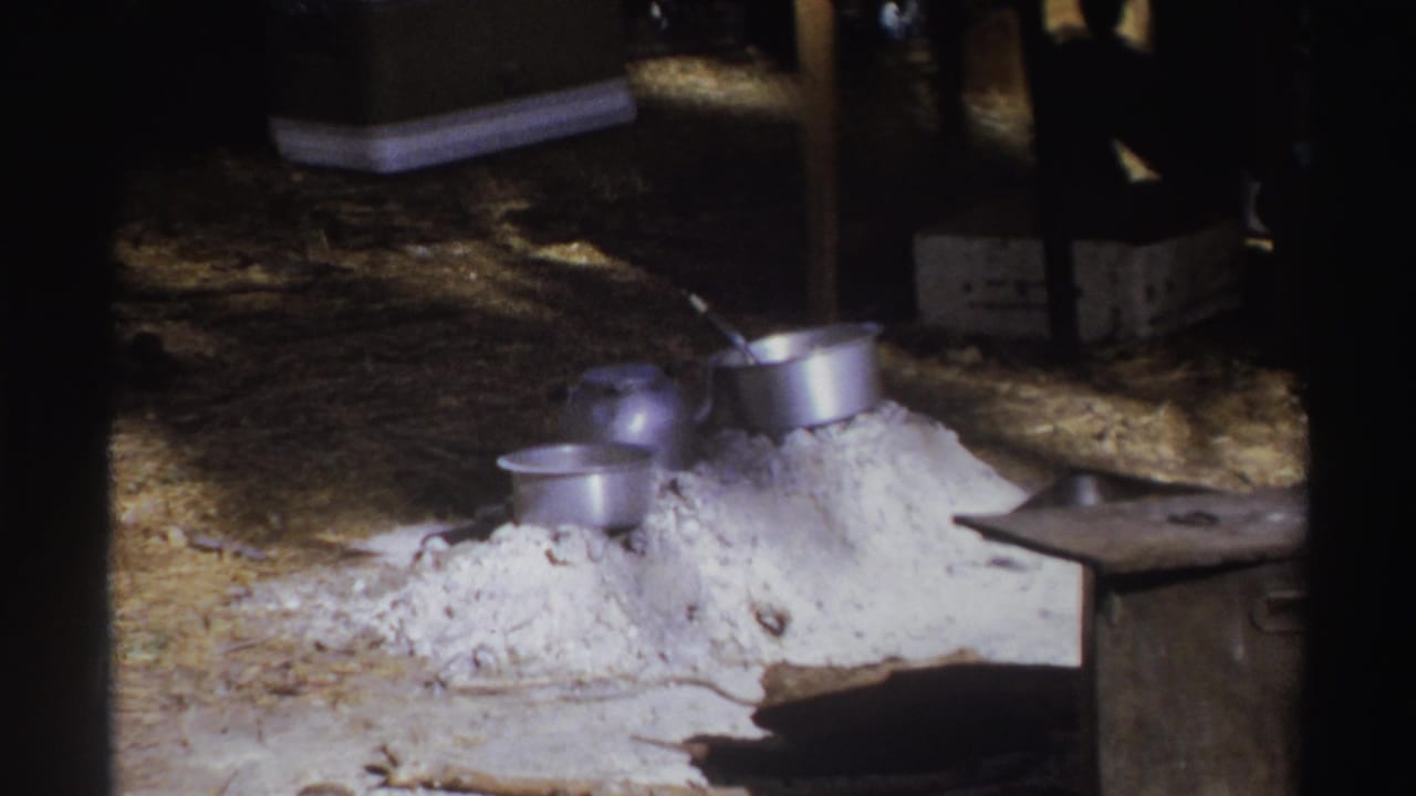 Pile of white ash or sand with metal pots and a dark storage box nearby.