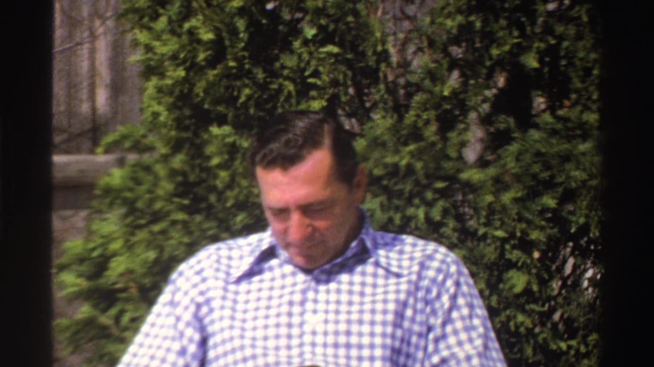 The 1969 Michigan footage shows a closer view of the seated man in a blue-and-white checkered shirt with greenery behind him.