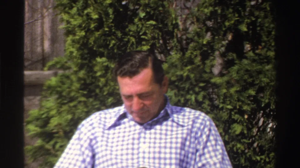 The 1969 Michigan footage shows a closer view of the seated man in a blue-and-white checkered shirt with greenery behind him.