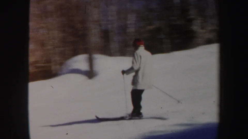 Side view of the skier on a snow-covered Vermont slope, with bare winter trees behind and visible 8mm softness.