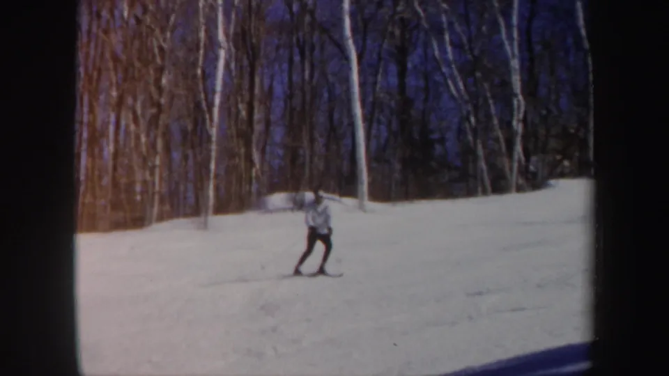 The skier, wearing a light jacket and dark pants, crosses the snowy Vermont slope in this 1962 home-movie frame.