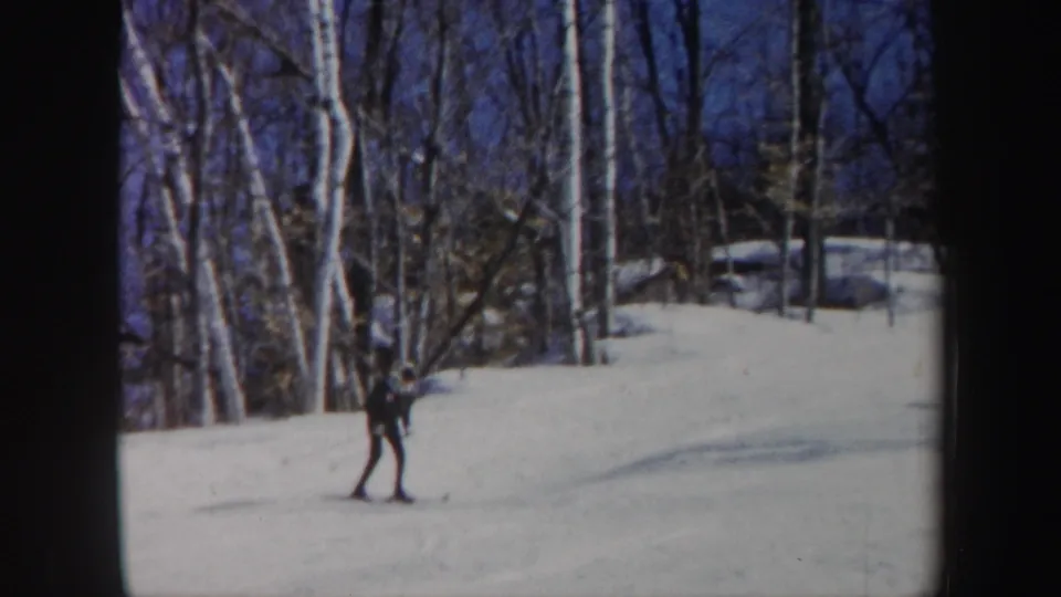 A lone skier appears to slow or stand on the snowy Vermont slope, surrounded by bare trees in small-gauge home-movie footage.
